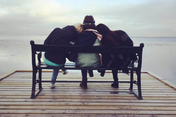 3 women sitting on a bench supporting each other - support a friend or loved one with depression